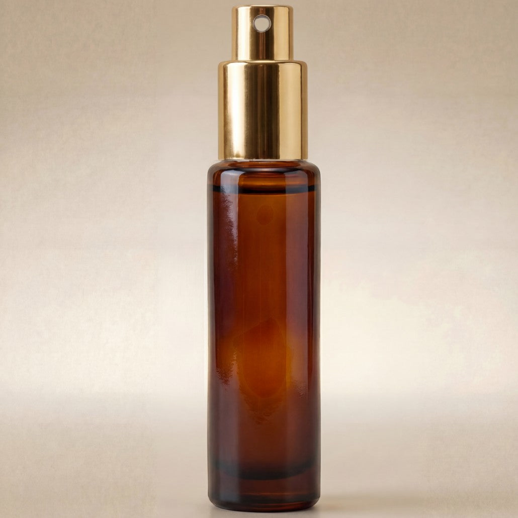 Brown glass spray bottle with gold cap on a beige background