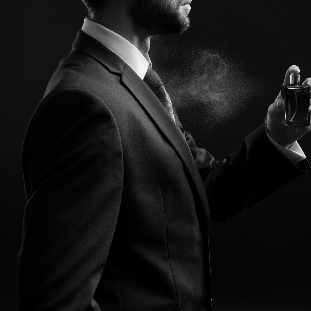 Man in tuxedo spraying colognue on chest