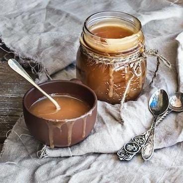 Jar of caramel sauce next to bowl of caramel sauce with spoon