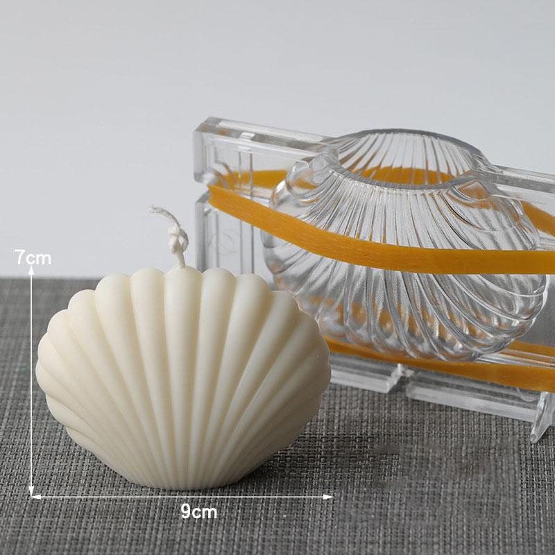 7cm high and 9cm wide clam shell candle with acrylic mould in background  on a grey textured table