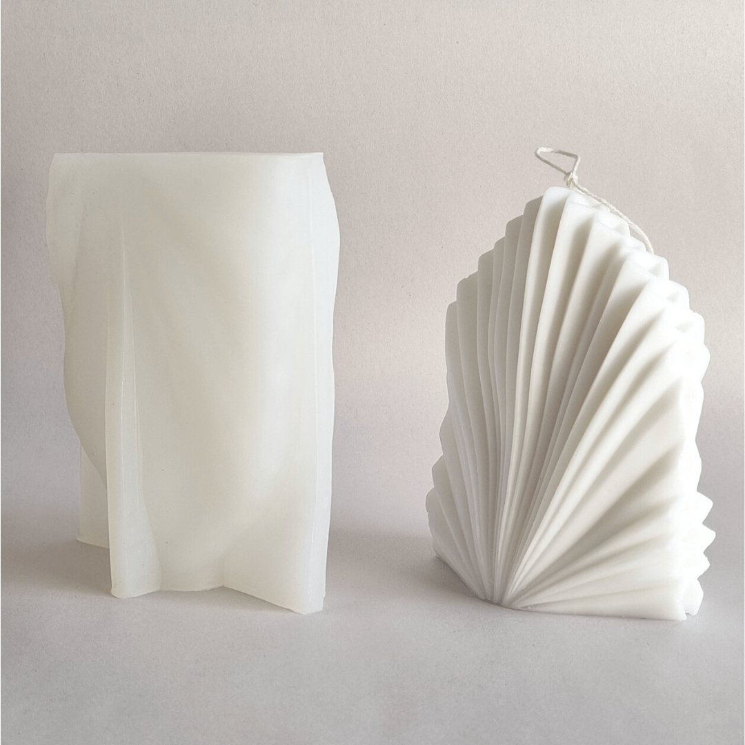 white fan candle next to fan candle mould in white silicone on a white background