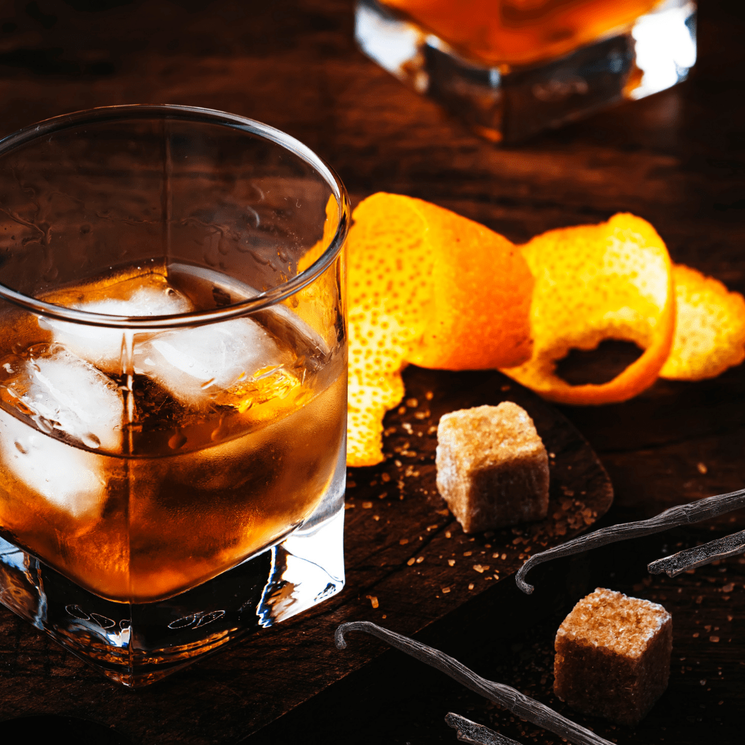 glass of boubon with orange peels, sugar cubes & vanilla bean