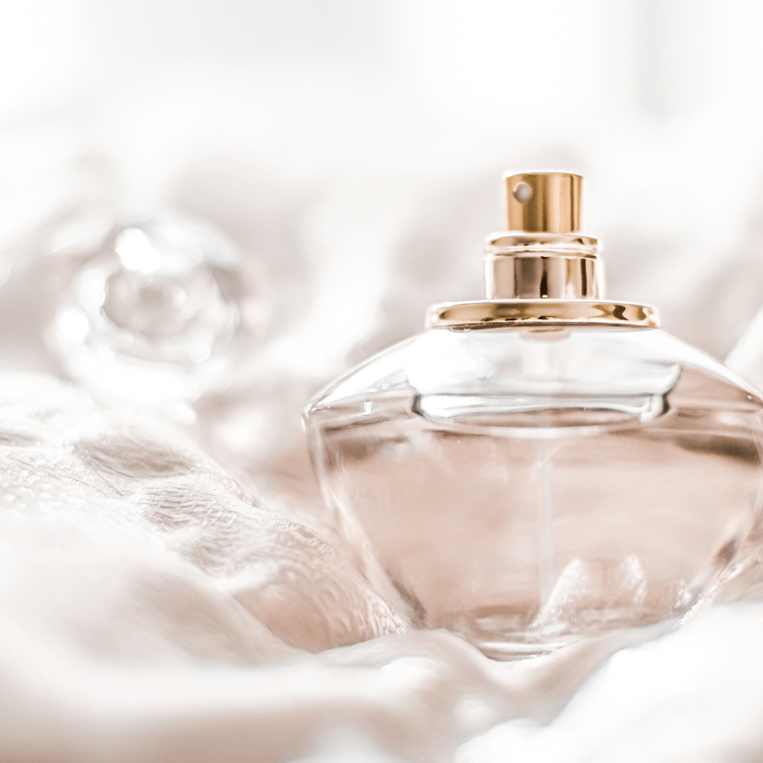Perfume bottle with gold and pink base resting on top of lace table cloth