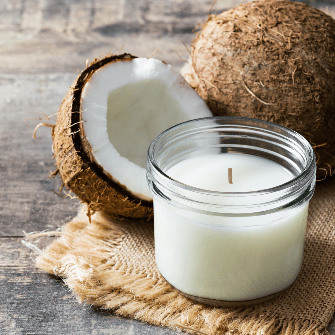 clear glass candle with coconuts in background resting on hessian runner