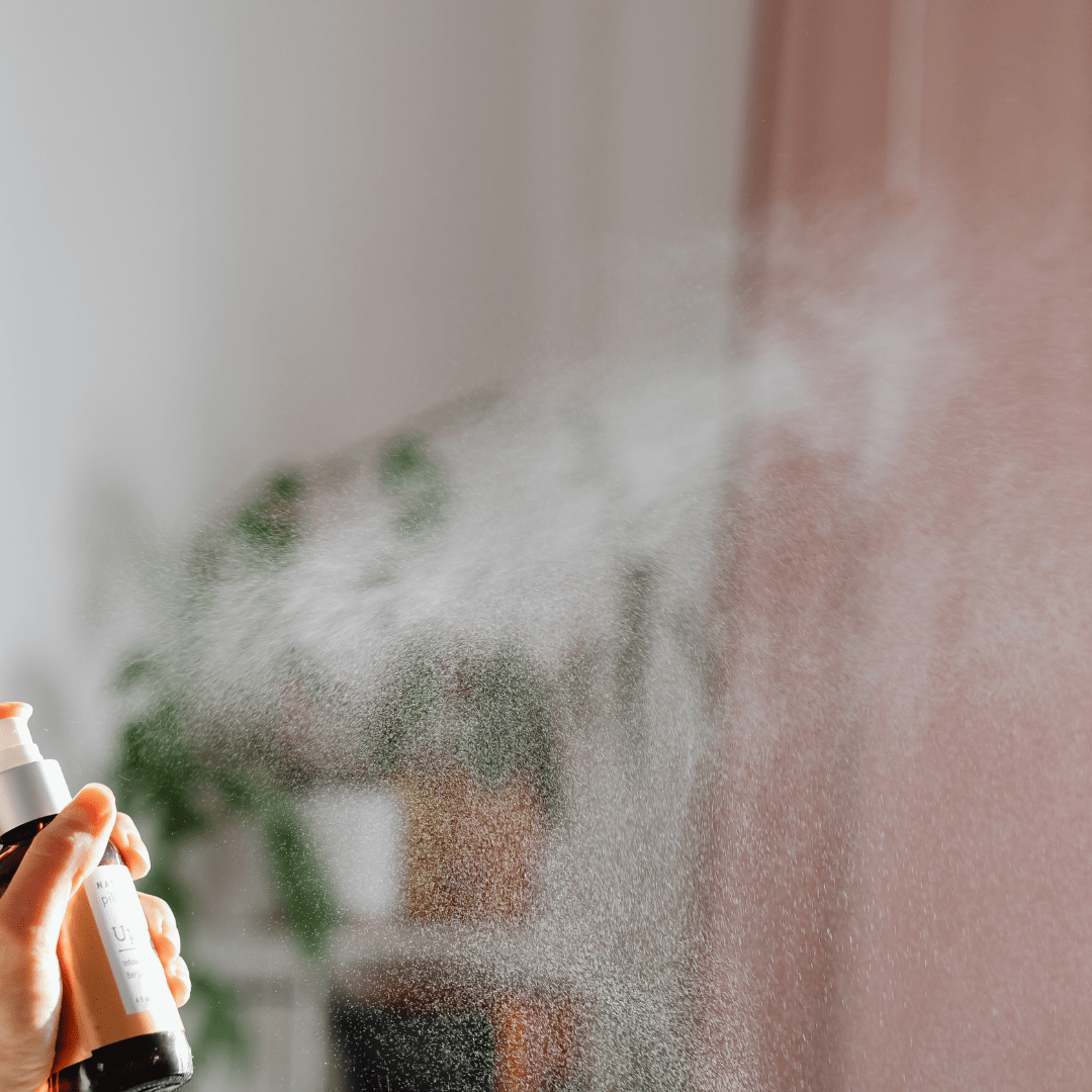 personal holding spray bottle with fragrance spraying out of nozzle