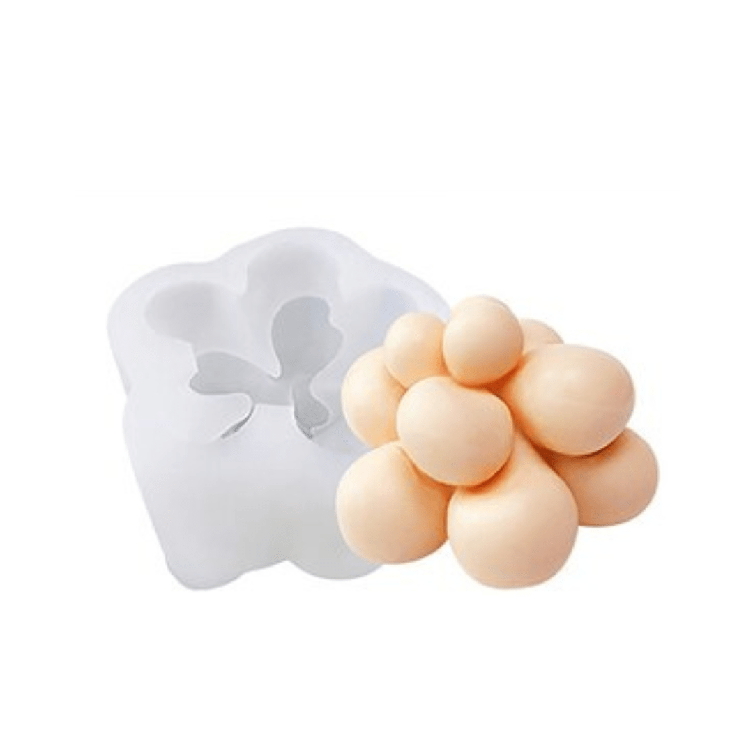 round succulent mould candle in peach wax next to silicone mould on white background