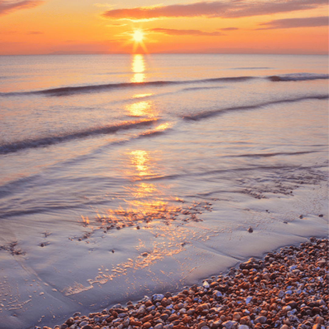 beach at sunset with pepples at shoreline