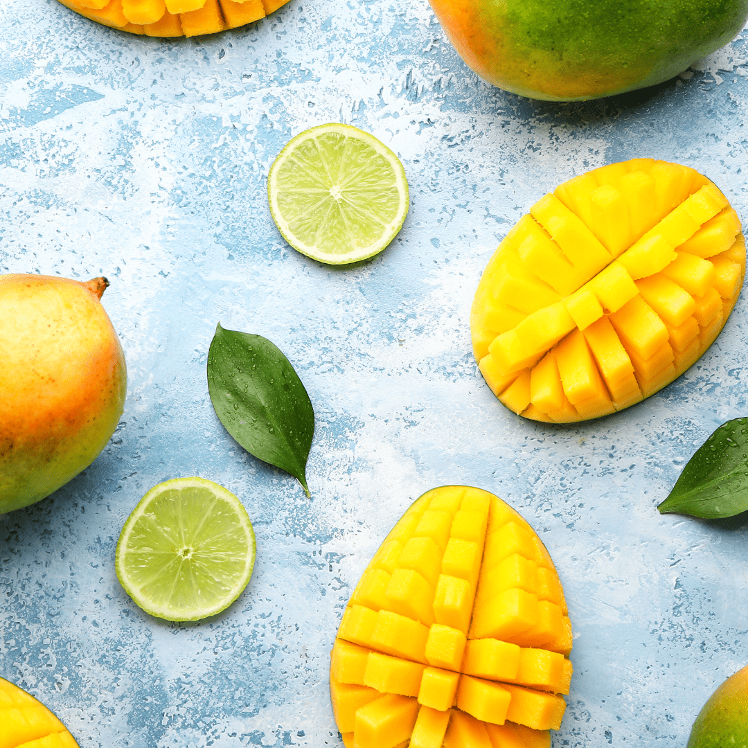 fresh cut mangos with lime slices and thai leaves