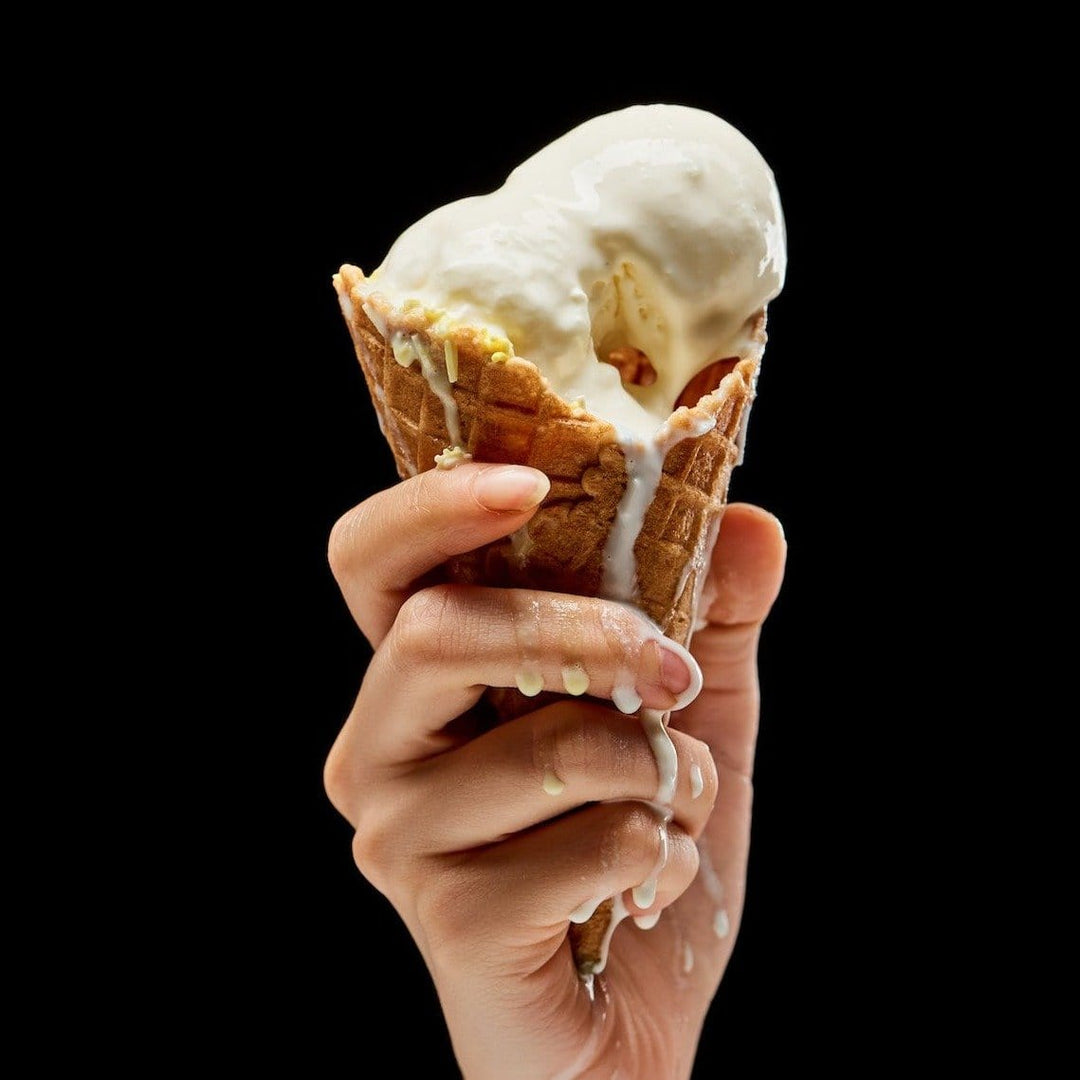 vanilla ice cream in waffle cone, melting onto hand
