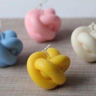 woven ball shaped candles in yellow blue white and pink against linen background