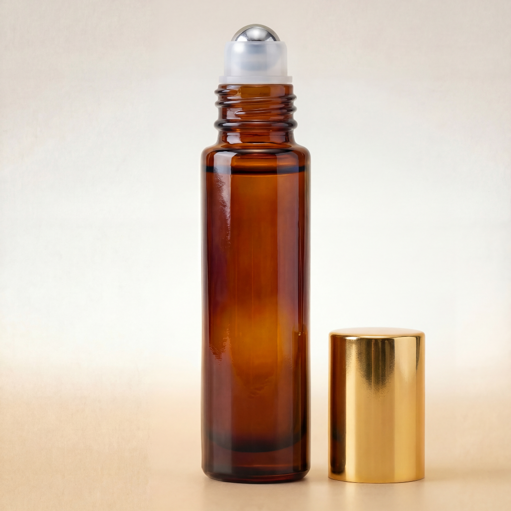 Amber glass roller bottle with silver cap and gold lid on a beige background