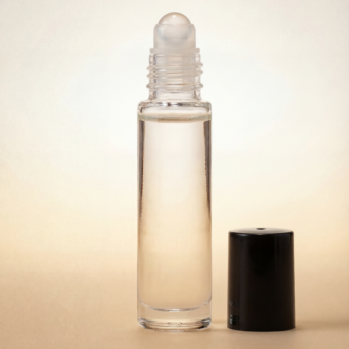 Clear glass roller bottle with black cap on a beige background