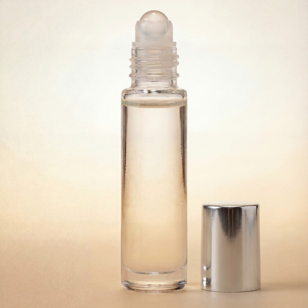 Clear glass rollerball bottle with silver cap on a beige background