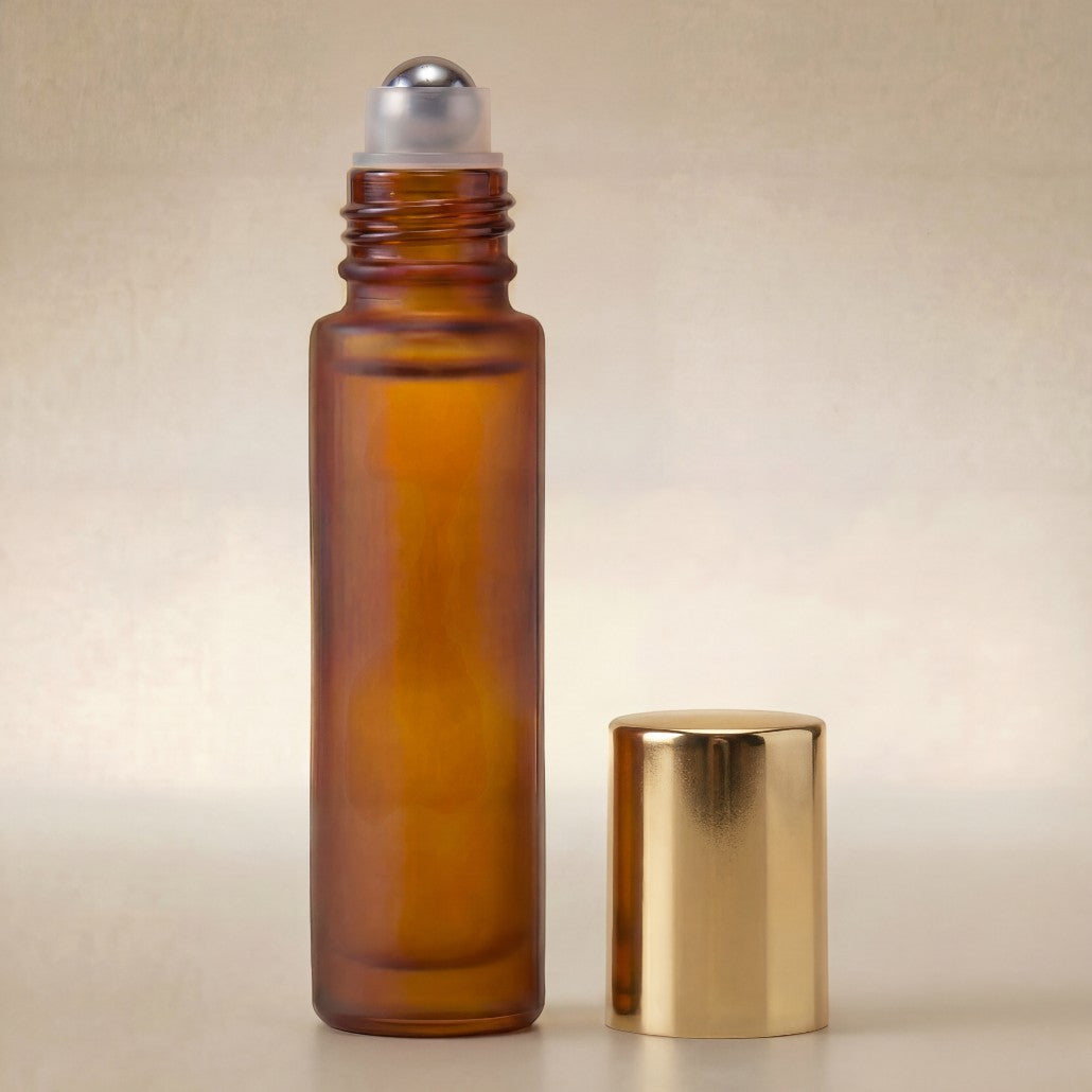 Amber glass roller bottle with gold cap on a beige background