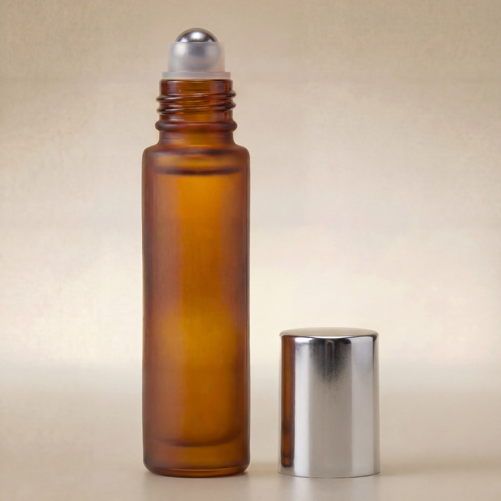 Amber glass roller bottle with silver cap on a beige background