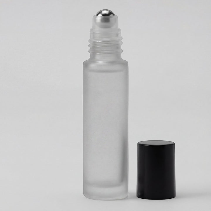 Clear glass roller bottle with silver cap and black cap on a light gray background
