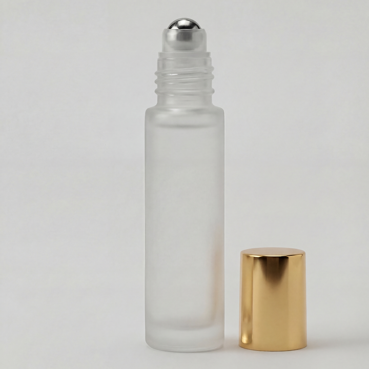 Glass roller bottle with silver cap and gold base on a light gray background