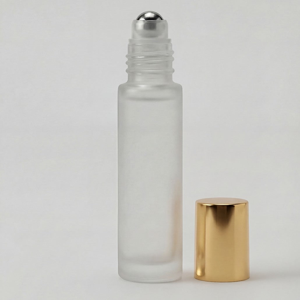 Glass roller bottle with silver cap and gold base on a light gray background