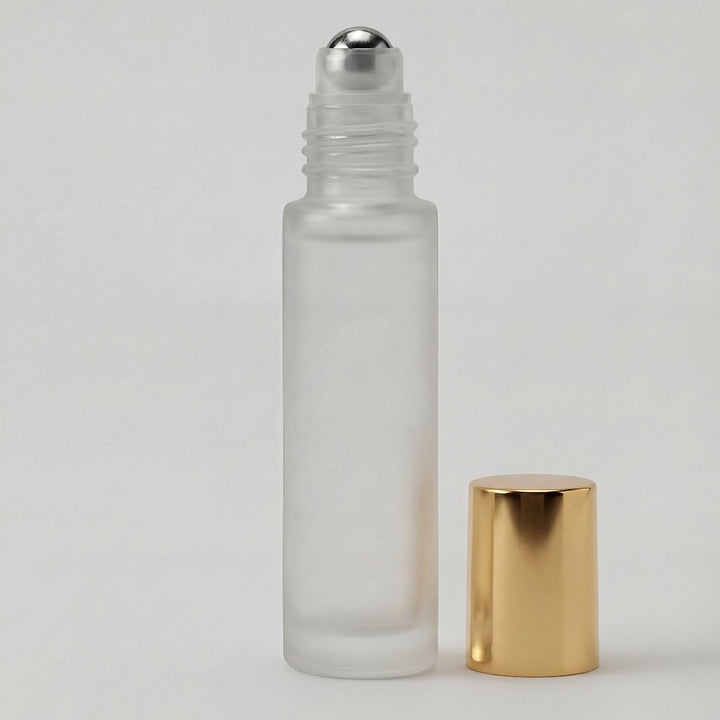 Glass roller bottle with silver cap and gold base on a light gray background