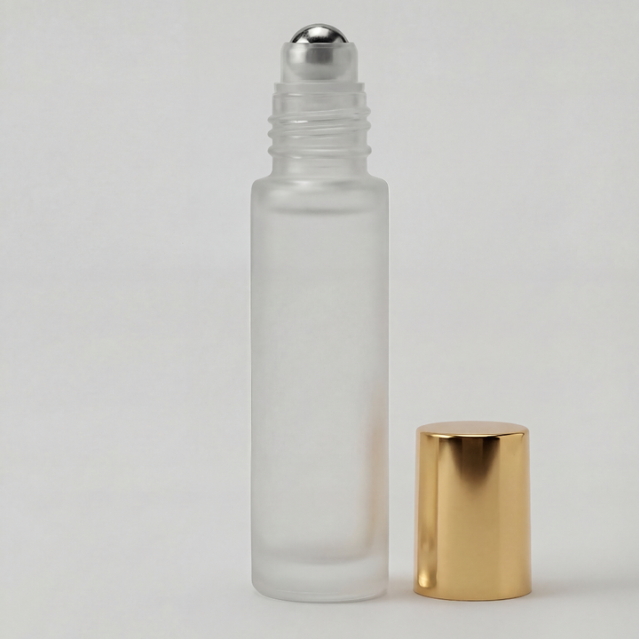 Glass roller bottle with silver cap and gold base on a light gray background