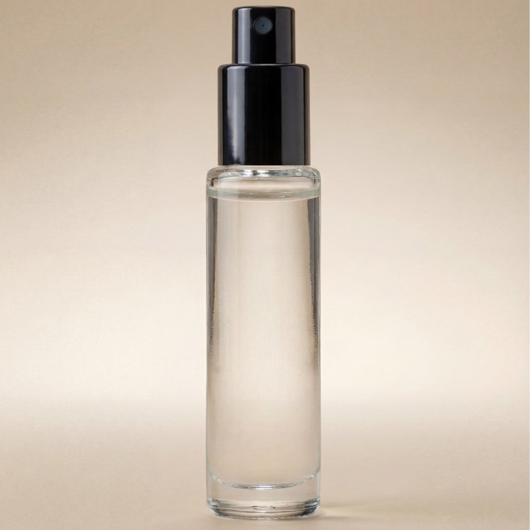 Clear spray bottle with black nozzle on a beige background