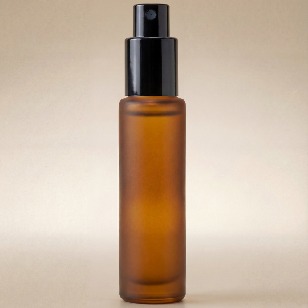 Amber glass spray bottle with black cap on a beige background