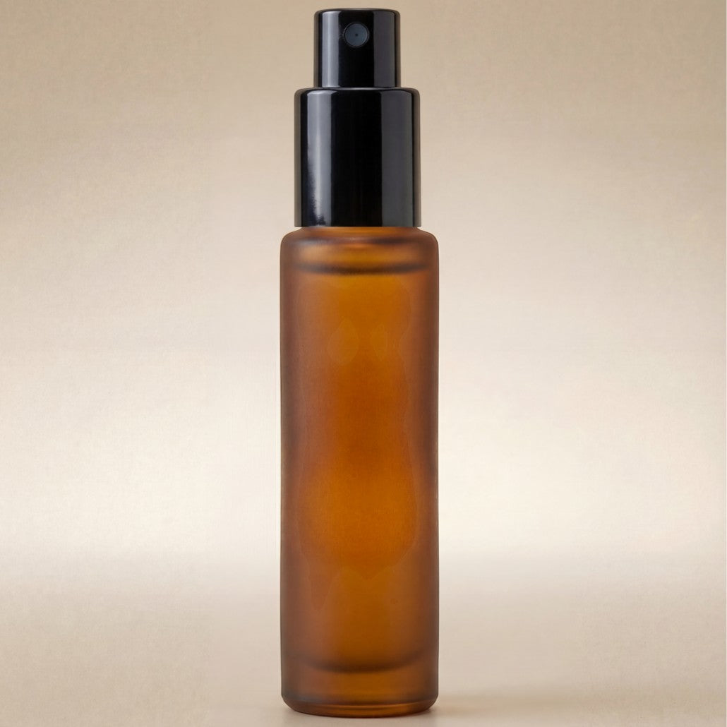 Amber glass spray bottle with black cap on a beige background