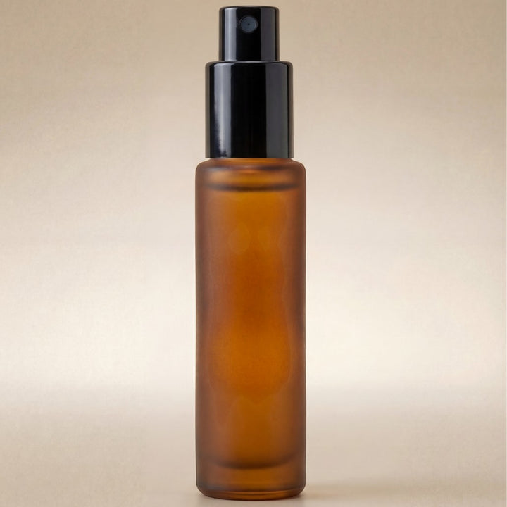 Amber glass spray bottle with black cap on a beige background
