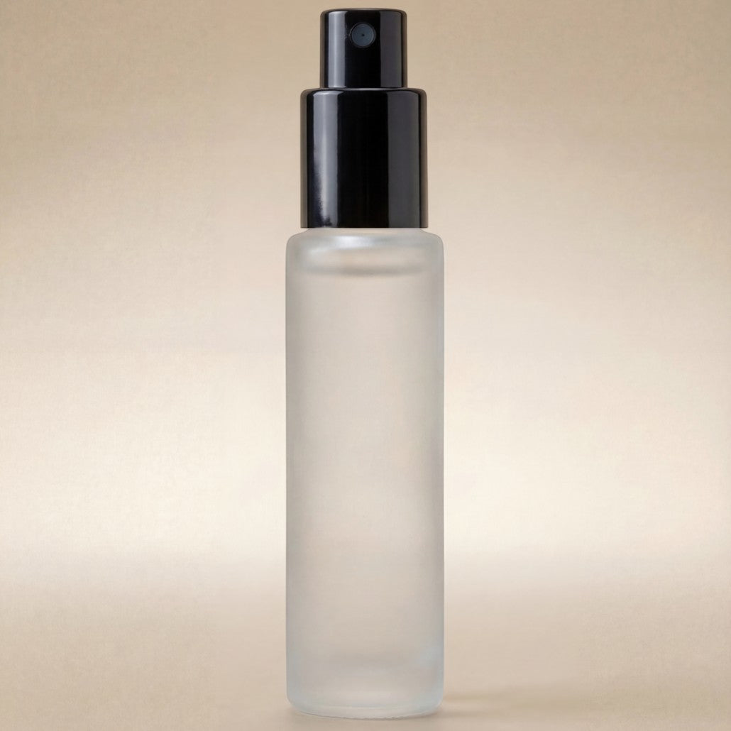 Clear glass bottle with black spray nozzle on a beige background