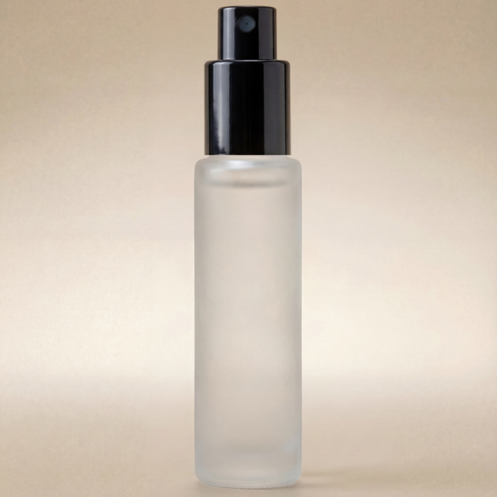 Clear glass bottle with black spray nozzle on a beige background