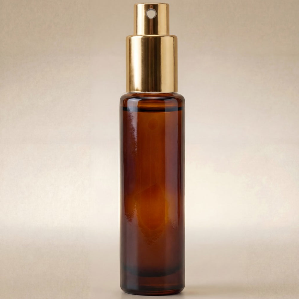 Brown glass spray bottle with gold cap on a beige background