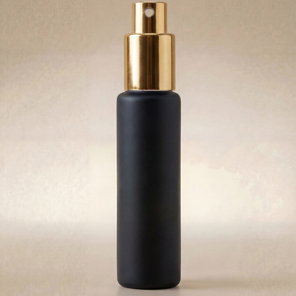 Black spray bottle with gold top on a beige background