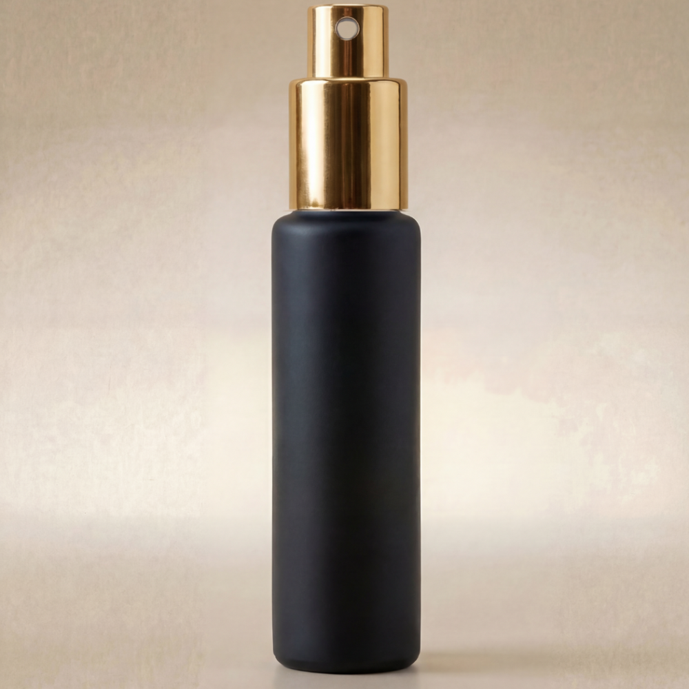Black spray bottle with gold top on a beige background