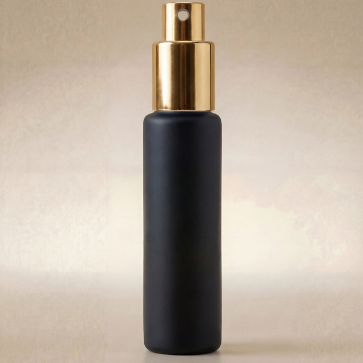 Black spray bottle with gold top on a beige background