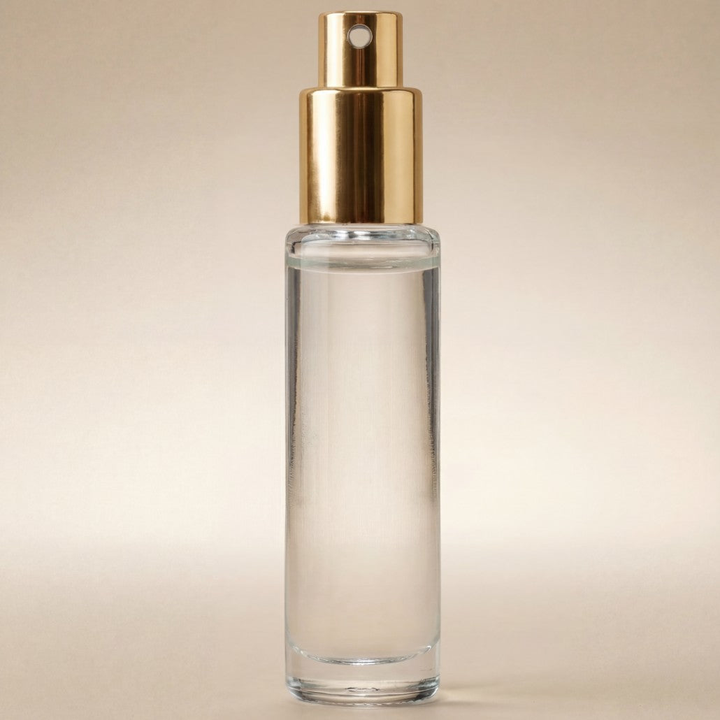 Clear glass bottle with gold cap on a beige background
