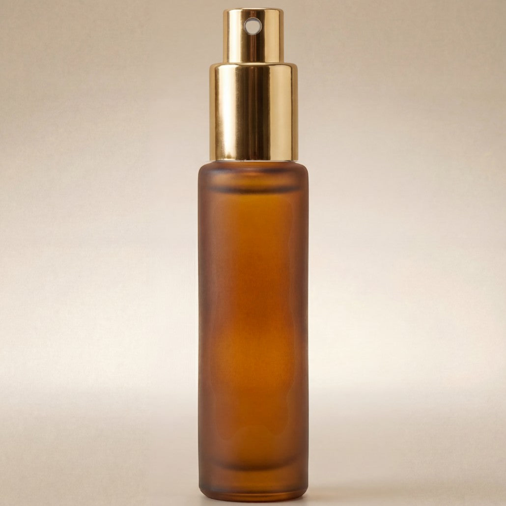 Amber glass spray bottle with gold cap on a beige background