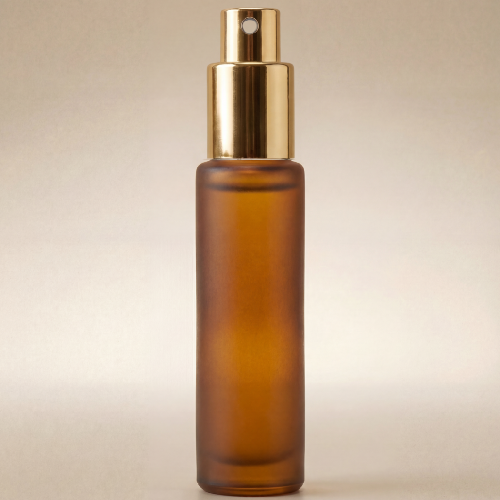 Amber glass spray bottle with gold cap on a beige background