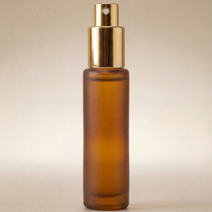 Amber glass spray bottle with gold cap on a beige background