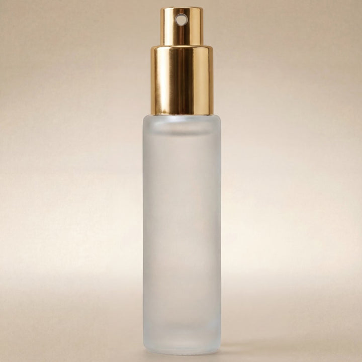 Frosted spray bottle with gold cap on a beige background