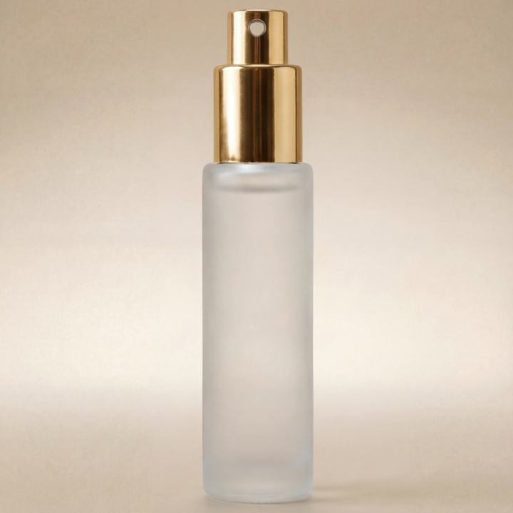 Frosted spray bottle with gold cap on a beige background