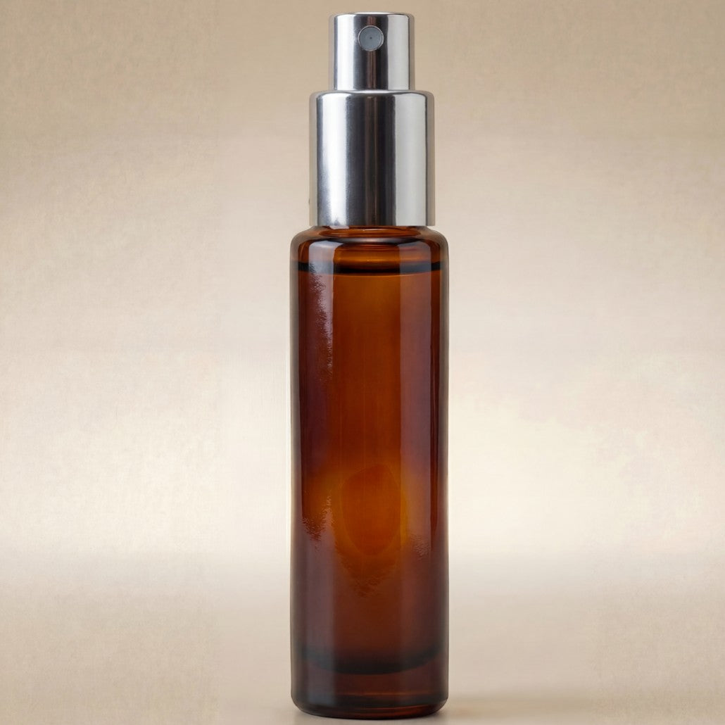 Amber glass spray bottle with silver nozzle on a beige background