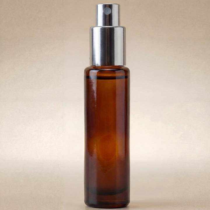 Amber glass spray bottle with silver nozzle on a beige background