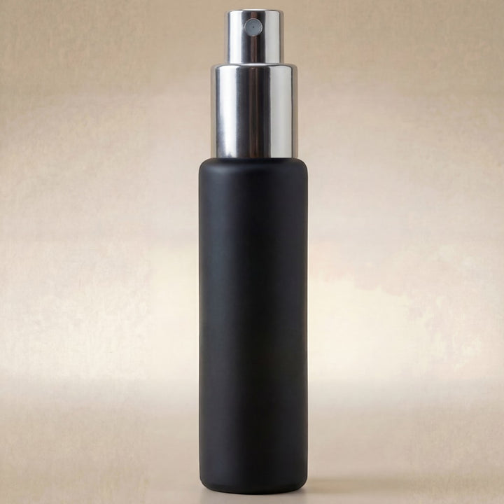 Black spray bottle with silver nozzle on a beige background