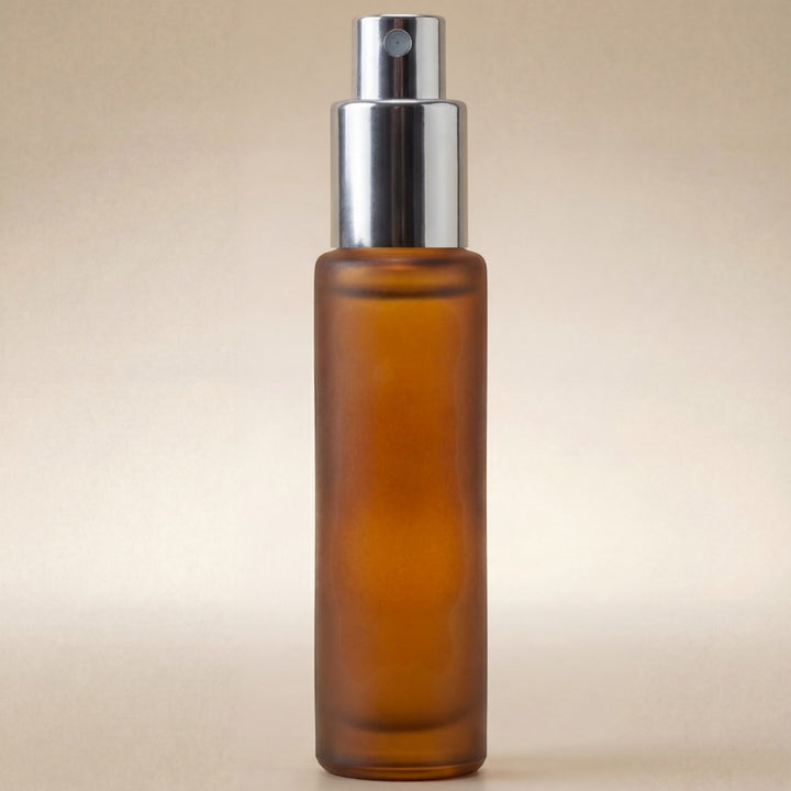 Amber glass spray bottle with silver nozzle on a beige background