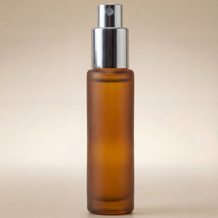 Amber glass spray bottle with silver nozzle on a beige background