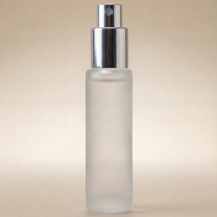 Frosted spray bottle with silver nozzle on a beige background
