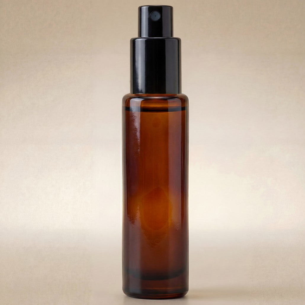 Amber glass spray bottle with black cap on a beige background