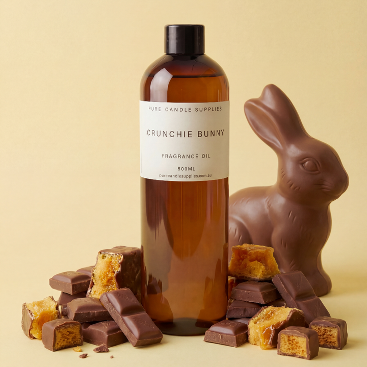 Bottle of Crunchie Bunny fragrance oil with a chocolate rabbit and pieces of chocolate on a beige background