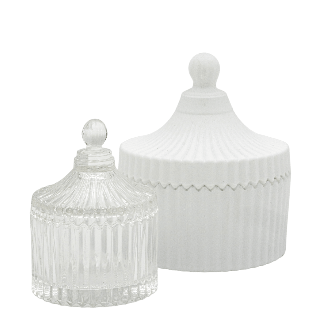 large matte white carousel style candle jar in background with small clear glass carousel style candle jar in foreground