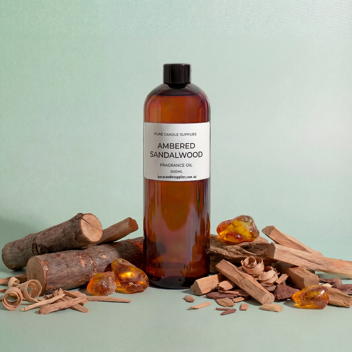 Bottle of ambered sandalwood fragrance oil with sandalwood pieces on a light green background